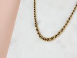 un gros plan d'un collier à chaîne en or posé sur une surface en marbre