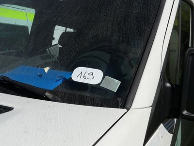 a white car with a sticker on it ' s windshield