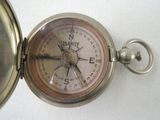 a close up of a silver pocket watch with a compass on it