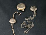 two pieces of silver jewelry sitting on top of a black table