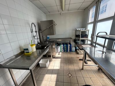 des tables et des bancs dans une cuisine équipée d'un évier et d'une grande fenêtre