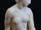 marble statue of a woman sitting on a rock with her hands on her knees