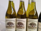 four bottles of wine are lined up on a white surface