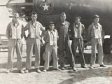 black and white photo of a group of men standing in front of an airplane