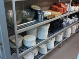 many plates and pans on the shelves in the kitchen
