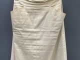 a white skirt hanging on a hanger against a gray wall