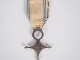 un gros plan d'une médaille posée sur une surface blanche, ornée d'une bande bleue