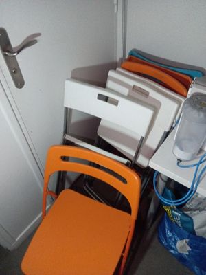 une pile de chaises orange et un ordinateur posé sur un bureau