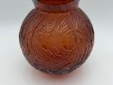 a brown glass vase with a brown lid on a white surface