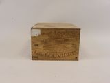 une vieille boîte en bois avec une étiquette posée sur une surface blanche