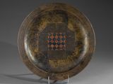 une assiette marron ornée d'un motif, posée sur un support en métal