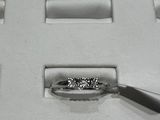 une bague en diamant dans une boîte blanche, accompagnée d'une paire de pinces