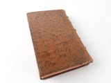 an old book with a brown cover sitting on top of a white surface