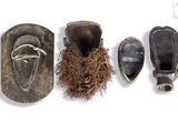three pairs of wooden shoes and a bird nest on a white surface