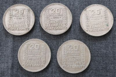 quatre types différents de pièces d'argent posées sur un tissu bleu