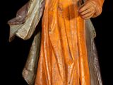 statue of a man with a hat and robe on a wooden base