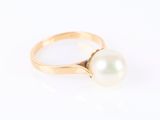 une bague en or ornée d'une perle blanche