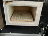 a black and white oven with a wooden tray inside of it