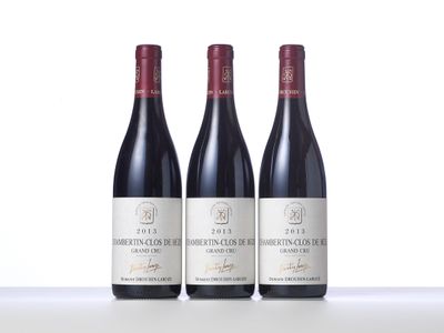 three bottles of red wine are lined up on a table