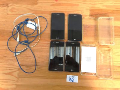 Plusieurs téléphones portables sont posés sur une table à côté d'un chargeur.