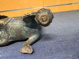 a bronze statue of a ram laying down on the floor