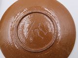 a brown bowl on a white table with a spoon in it