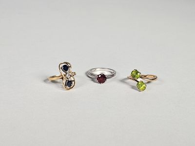 trois bagues différentes ornées de pierres de couleurs variées sur un fond blanc