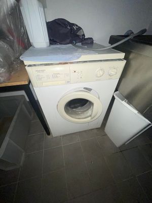 une machine à laver posée sur un plan de travail, à côté d'une poubelle