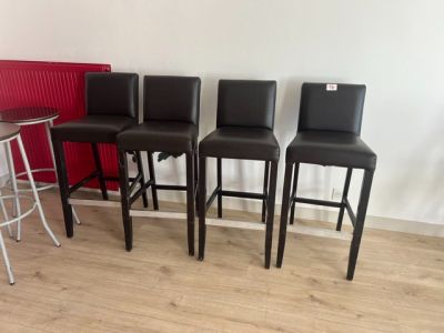 quatre tabourets de bar en cuir noir et une table dans une pièce