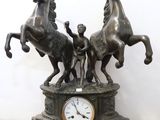 a statue of three horses and a clock on a table