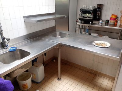 une cuisine équipée d'un évier et d'un plan de travail sur lequel est posée une assiette