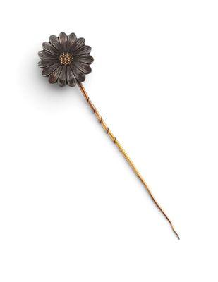 a close up of a metal flower on a stick on a white surface