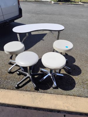 plusieurs tabourets et une table dans un parking, avec une camionnette en arrière-plan