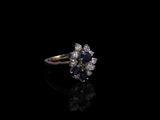 un gros plan d'une bague sertie d'un diamant et d'un saphir sur une surface noire