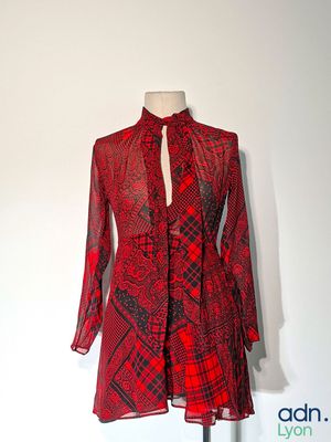 une robe rouge et noire posée sur un présentoir pour mannequin