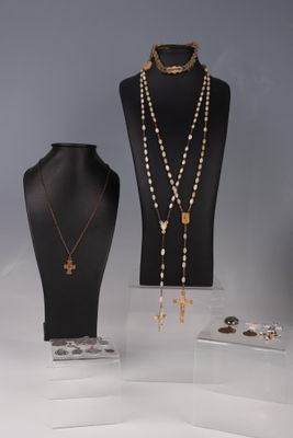 trois colliers et une croix exposés dans une vitrine