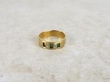 a close up of a gold ring with emerald stones