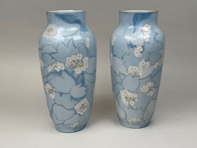une paire de vases bleus ornés de fleurs blanches sur fond blanc