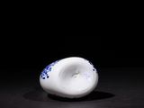 a white and blue vase sitting on a black surface
