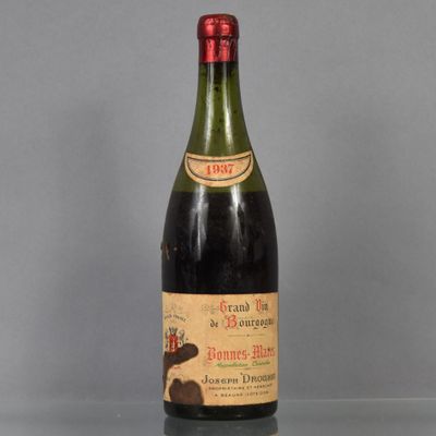 une vieille bouteille de vin posée sur une table en verre