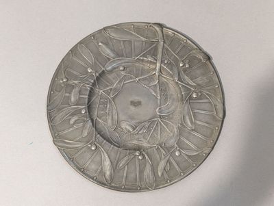 a silver plate with a design on it on a white surface