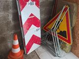 un panneau rayé de rouge et de blanc à côté d'un tas de panneaux de chantier