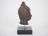 a bronze head of a buddha statue on a marble base