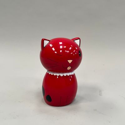 une figurine de chat rouge posée sur une surface blanche
