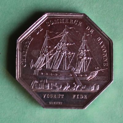 a silver coin with a picture of a ship on it