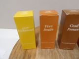 three boxes of perfume sitting on top of a wooden table next to each other