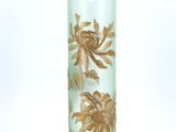 un vase vert orné de fleurs dorées