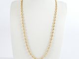 un collier à chaîne en or orné de perles, porté par un mannequin