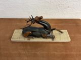 a bronze sculpture of a deer laying down on a table