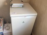 a small white refrigerator in the corner of a room